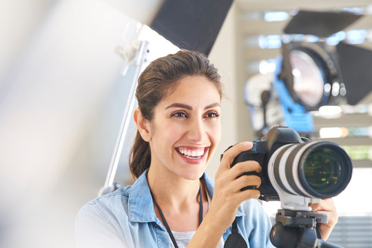Smiling female photographer behind camera in studio