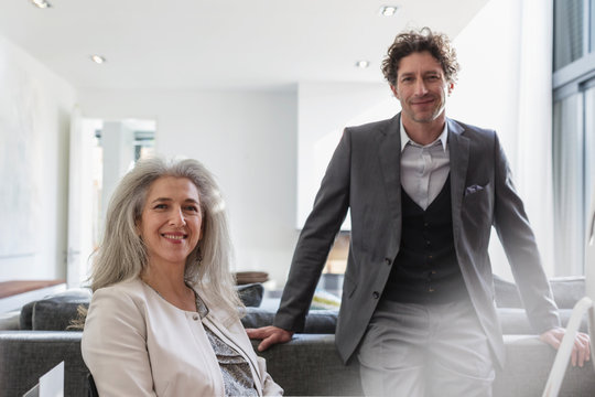 Portrait confident businessman and businesswoman in living room