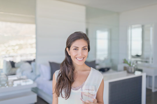 Portrait smiling brunette woman drinking water in bedroom