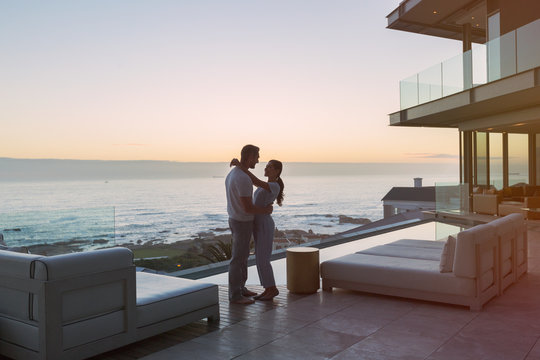 Affectionate couple hugging on luxury patio with ocean view - Powered by Adobe