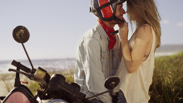 Affectionate young couple at motorcycle with beach in background