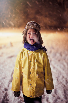 Boy in warm clothing sticking tongue out, tasting snow