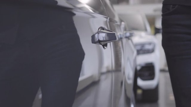 Unrecognizable Caucasian man in elegant outfit coming to automobile and opening car door. Owner taking his car back after repair. Car business, warranty service.