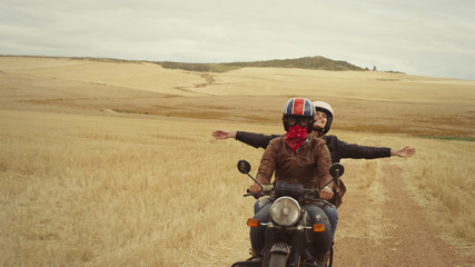 Exuberant young woman riding motorcycle in rural countryside