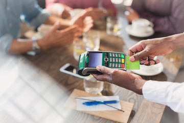 Waiter using credit card reader at restaurant table