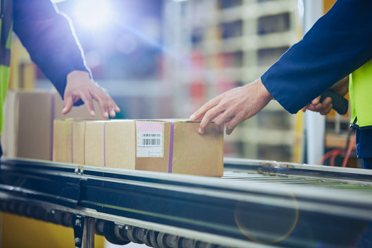 Workers scanning and processing boxes on conveyor belt in distribution warehouse