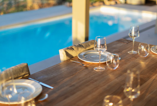 Placesettings on wood patio table at poolside