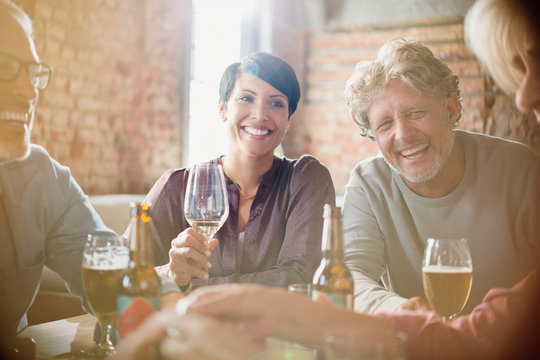 Laughing couples drinking white wine and beer at restaurant table