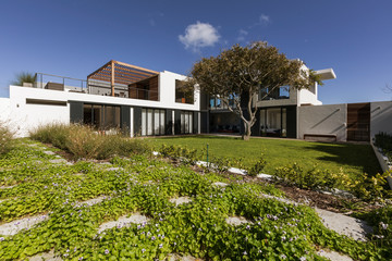 Sunny luxury modern home showcase exterior with sunny yard and tree