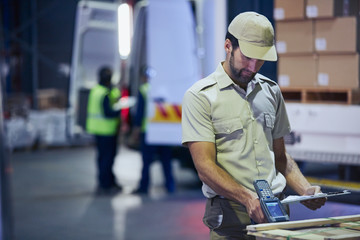Truck driver worker scanning pallet at distribution warehouse loading dock