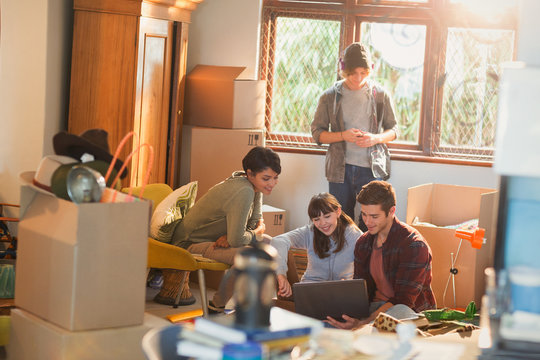Young couples roommates using laptop surrounded by moving boxes