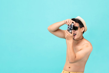 Young shirtless amazed Asian male tourist taking photo with camera
