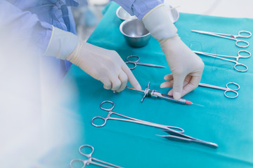 Surgeon in rubber gloves preparing surgical instruments on tray