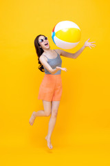 Happy young Asian woman in casual summer clothes playing beach ball