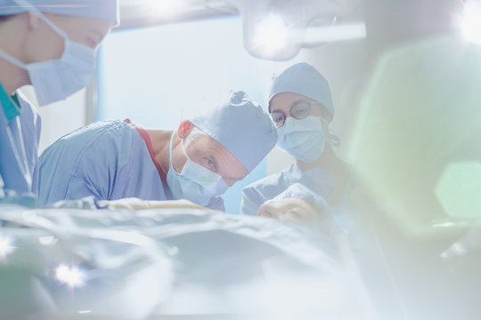 Focused male surgeon performing surgery on female patient in operating room