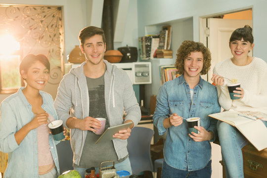 Portrait smiling young college student roommates studying eating instant noodles in apartment