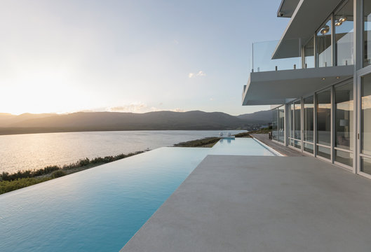 Sunny, tranquil modern luxury home showcase exterior with infinity pool and sunset ocean view