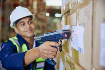 Worker with scanner scanning barcode on box in distribution warehouse