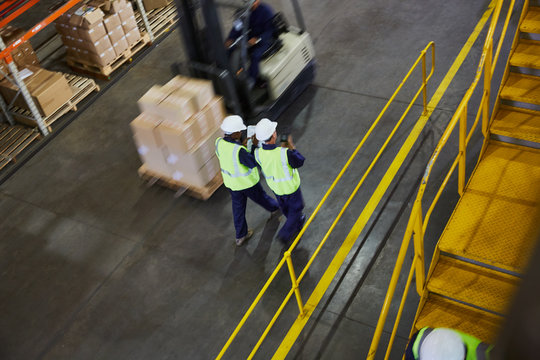 Forklift and workers on the move in distribution warehouse