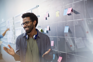 Happy, confident creative businessman planning, scheduling at calendar blackboard