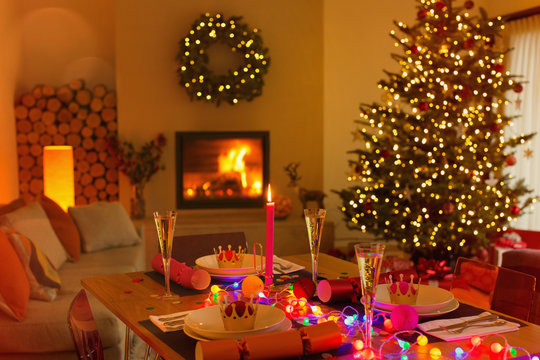Ambient Christmas dinner table in living room with fireplace and Christmas tree