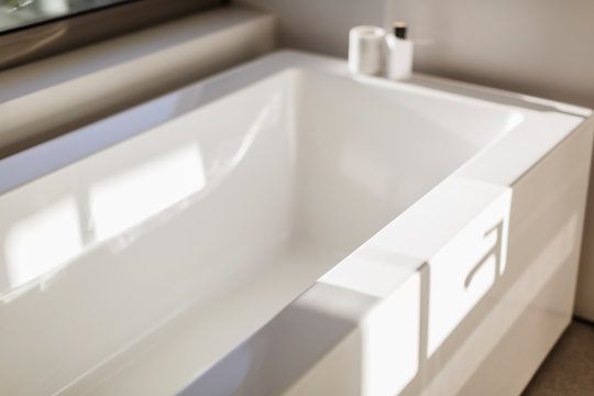 Sunny reflection over modern white bathtub