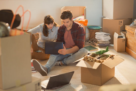 Young Couple Using Laptop Surrounded By Moving Boxes