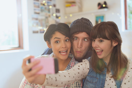 Playful young friends taking selfie making silly faces