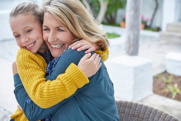 Enthusiastic grandmother and granddaughter hugging on patio