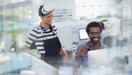 Smiling computer programmers programming virtual reality simulator in office
