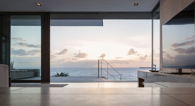 Home showcase living room and patio with tranquil sunset ocean view
