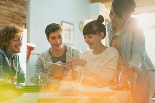 Young couples celebrating birthday opening gift at table
