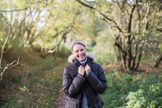 Portrait confident mature woman in parka in sunny autumn woods