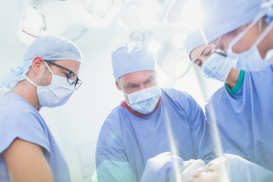 Focused surgeons and anesthesiologist preparing patient for surgery in operating room