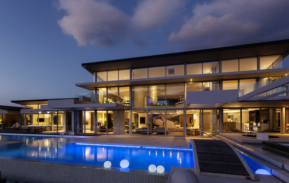 Illuminated modern luxury home showcase exterior with swimming pool at night