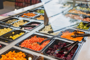 Salad bar items and tongs in grocery store market