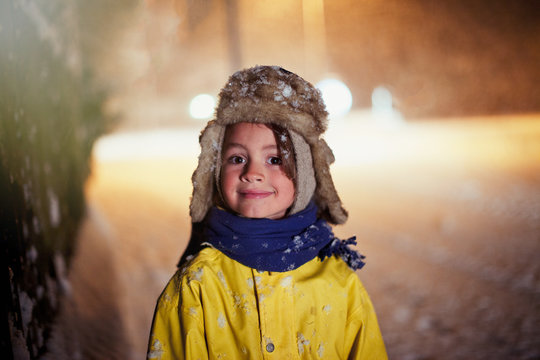 Portrait smiling boy in warm clothing standing in snowy road