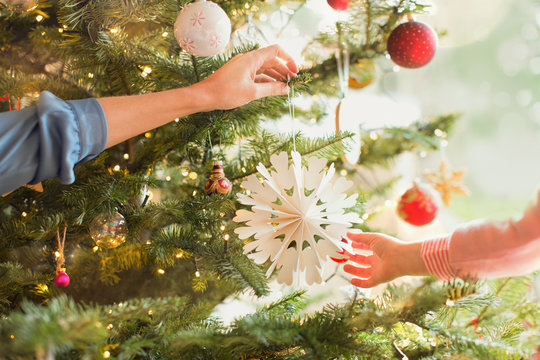 Mother and daughter hanging snowflake ornament on Christmas tree