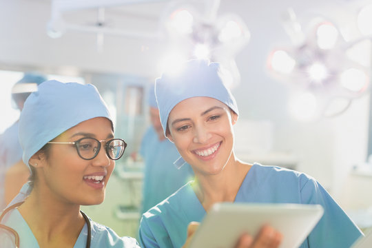 Female surgeons using digital tablet, talking in operating room