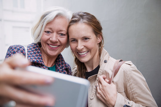 Smiling mother and daughter taking selfie with camera phone