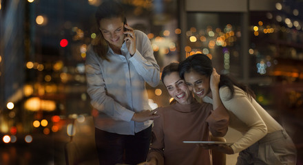Happy businesswomen celebrating, working late in office at night