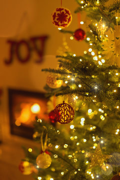Ornaments hanging from Christmas tree with string lights in living room