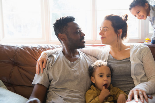 Affectionate multi-ethnic young family on living room sofa