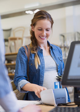 Smiling woman using credit card reader in shop