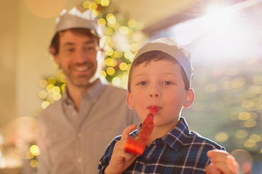Portrait boy wearing Christmas paper crown blowing party favor