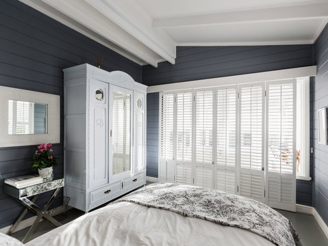 Luxury home showcase bedroom with white wood shutters and vaulted ceiling