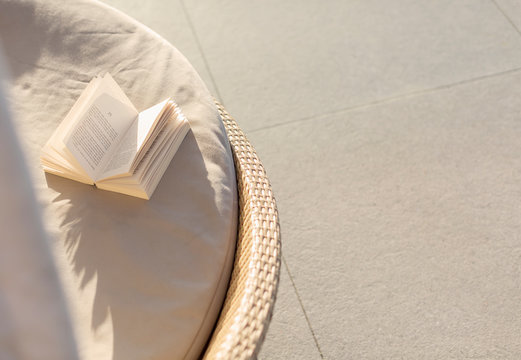 Open book on sunny lounge chair