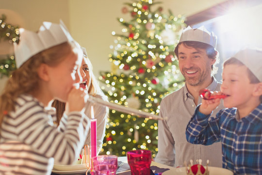 Family Wearing Paper Crowns At Christmas Dinner Table