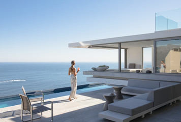 Woman on sunny modern, luxury home showcase exterior patio with ocean view