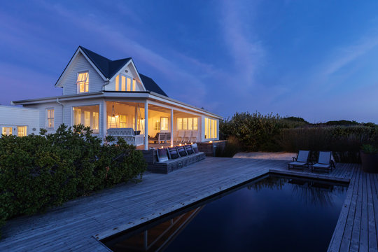 Illuminated white home showcase exterior and swimming pool at night